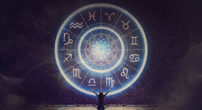 Person gazing at glowing zodiac wheel in the night sky symbolizing best astrologer near me