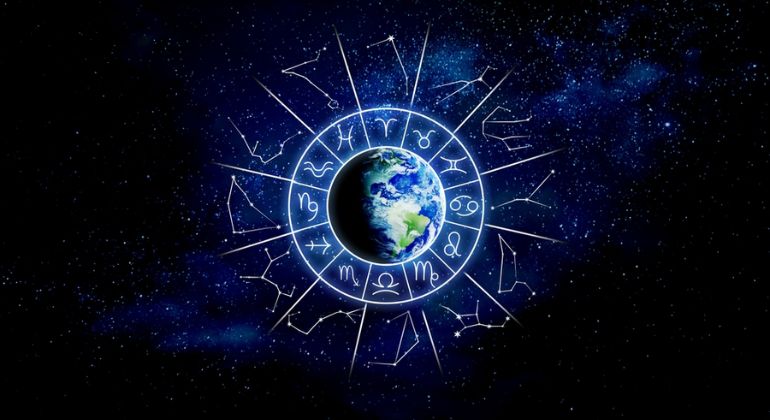 Planet Earth at the center of a glowing zodiac wheel with astrological symbols, set against a deep space background filled with stars, representing online astrology expertise in India.